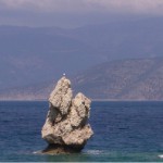 An isolated rock in the sea - Alkyonides Gulf, Greece. Not only great landscape there, but also good beaches. Be aware of sea urchins if you go there, I've seen too many students with tweezers, trying to remove every single spine from their feet...